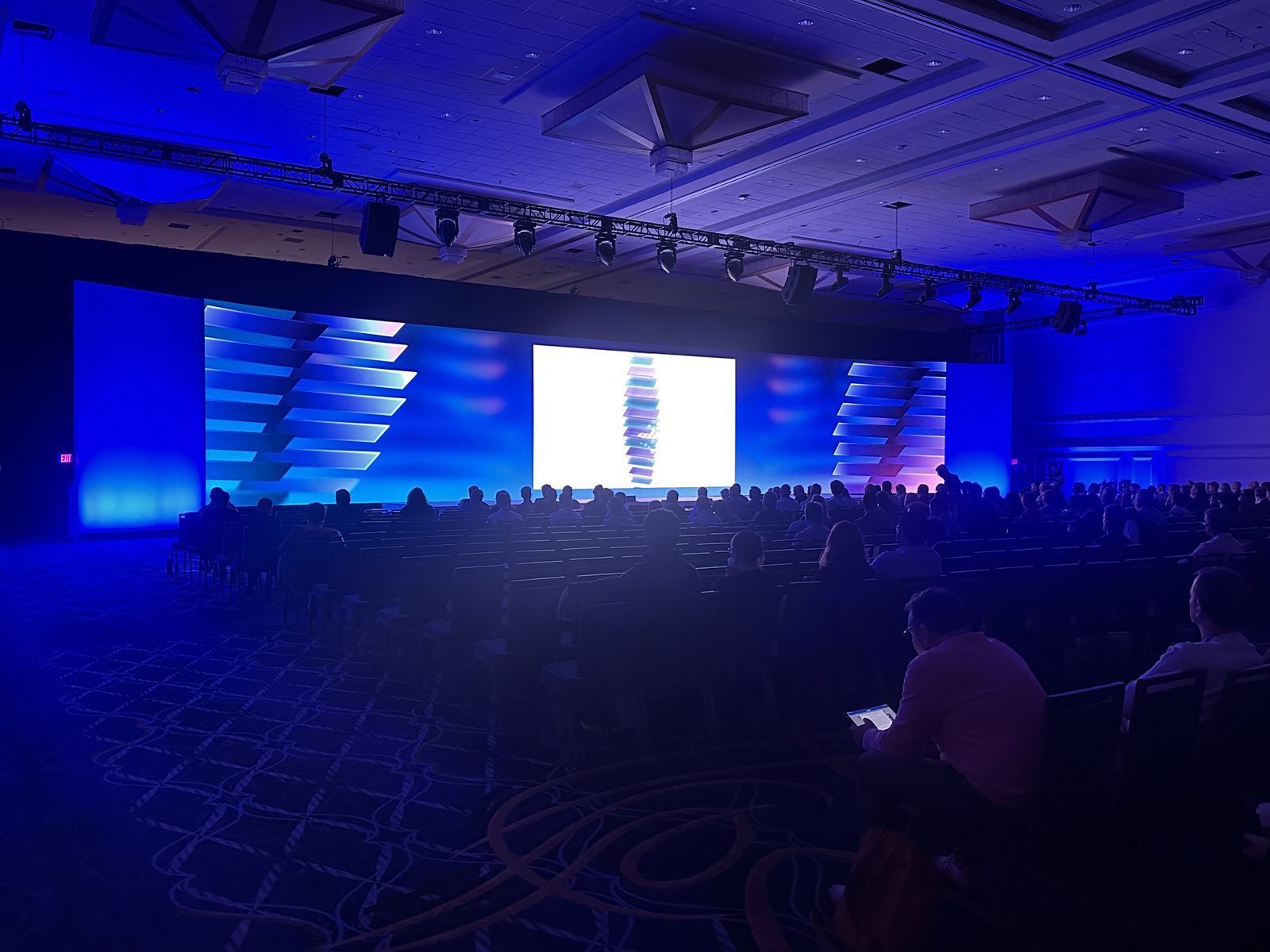 Large general session with LED walls, moving-head lighting and a full audience