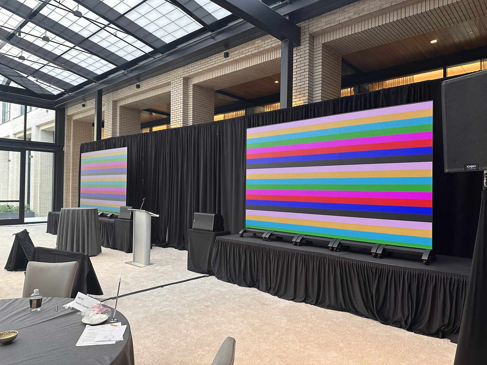 Two LED video walls with a podium, staged in a glass-roofed atrium